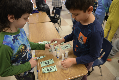 Students exchange money and goods in class activity.
